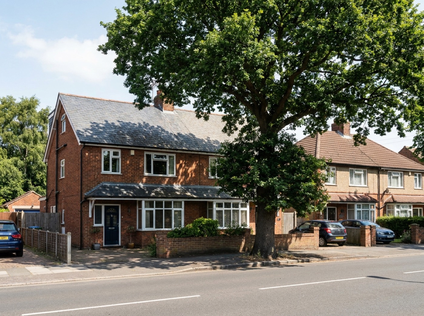 A brick semi-detached house with a large oak tree shading part of its roof; the unshaded half is traced