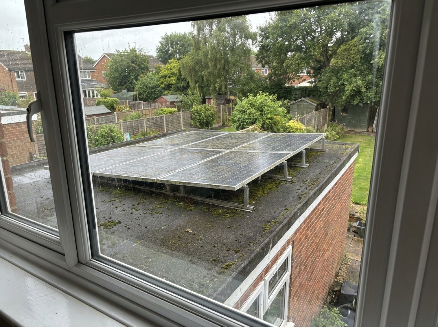 A flat garage roof seen from an upstairs window, with panels mounted on tilted frames; the roof is traced